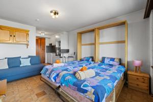 una camera con un grande letto e un divano blu di Arnica 2 - 2 pers - piscine a Nendaz Altre 21 foto