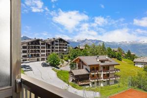 e balcone con vista su un resort con montagne. di Arnica 2 - 2 pers - piscine a Nendaz