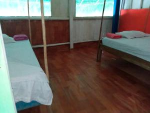 a room with two beds and a wooden floor at Ayahuasca y Turismo in Tamshiyacu