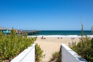 een strand met een pier en mensen op het zand bij Nags Head Oceanfront Private Beach Access & Pool in Nags Head