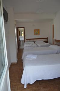 a row of four white beds in a room at Hostería Somo in Somo