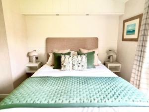 a bedroom with a large bed with green sheets and pillows at Hollicarrs - Oak Tree Lodge in Riccall +25 photos