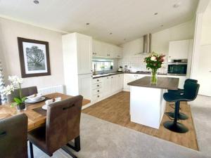 a kitchen with white cabinets and a wooden table at Hollicarrs - Oak Tree Lodge in Riccall