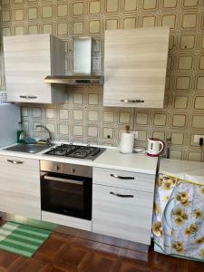 a kitchen with white cabinets and a stove top oven at Mi 'ffaciu e mi ricriu casa vacanze in Castelmola