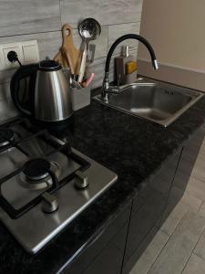 a kitchen counter with a stove and a sink at Cozy studio with a balcony and sea view in Batumi +17 photos