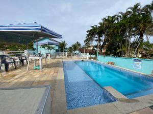 a swimming pool with a table and a umbrella at Chalés Céu e Mar Ubatuba in Ubatuba