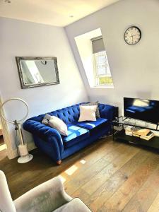 Un sofá azul en una sala de estar con un reloj. en Superb luxury 2 beds in Victoria Pimlico Westminster, en Londres