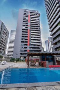 a large building with a swimming pool in front of it at Flat c/ Limpeza Diária | Piscina e Praia - DL1804 in Recife