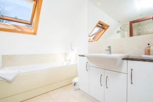 ein weißes Badezimmer mit einem Waschbecken, einer Badewanne und einem Spiegel in der Unterkunft 5 Mariners Reach in Saundersfoot + 30 Fotos