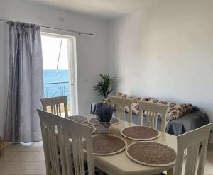 a dining room with a table and chairs and a window at Enopia Apartments Himara in Himare