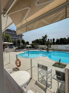 a swimming pool with chairs and a table and an umbrella at Hotel Bella Igea in Bellaria-Igea Marina