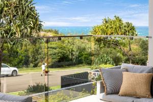 a balcony with a view of a person walking a dog at Seaside Luxury: Private Pool and Stunning Views in Yaroomba