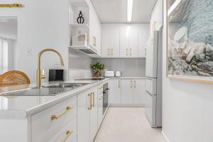 a white kitchen with a sink and a refrigerator at Amalfi on Alex: Seaside 2 Bedroom Retreat in Alexandra Headland