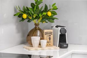 a vase with a plant and two cups on a counter at Amalfi on Alex: Seaside 2 Bedroom Retreat in Alexandra Headland