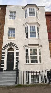 une maison blanche avec une porte noire et une clôture dans l'établissement Grade II Townhouse - Relax & Discover Margate, à Margate