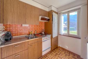 a kitchen with wooden cabinets and a sink and a window at With Mountain View & Balcony Kitchen Parking in Kandersteg