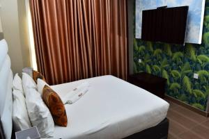 a hotel room with a bed with white sheets at Polka GuestHouse in Tshabong