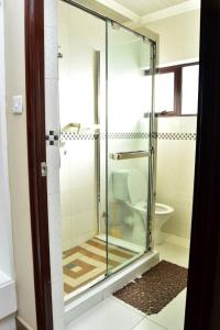 a glass shower in a bathroom with a toilet at Polka GuestHouse in Tshabong