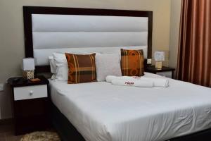a bedroom with a large white bed with pillows at Polka GuestHouse in Tshabong