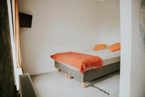 a bedroom with a bed with an orange blanket on it at Park Hotelik II Piętro in Mielno