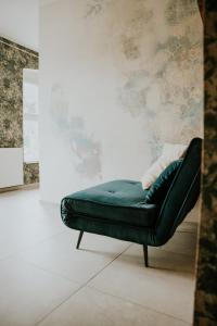 a green couch in a room with a wall at Park Hotelik II Piętro in Mielno