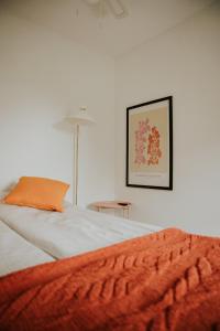 a bedroom with a bed with an orange pillow and a table at Park Hotelik II Piętro in Mielno
