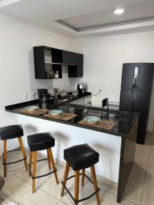 a kitchen with a large black counter with stools at CASA Aconchegante Sorocaba Itu in Sorocaba