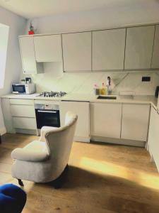 cocina blanca con silla y fogones en Superb luxury 2 beds in Victoria Pimlico Westminster, en Londres