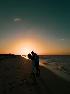 a couple kissing on the beach at sunset at Aura De Rio in Río Lagartos