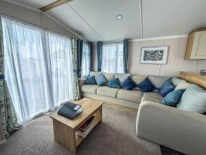 ヘムズビーにあるStunning Caravan With Side Decking Just A Short Walk To Hembsy Beach Ref 00069Baのリビングルーム(大きなソファ、青い枕付)