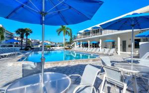a pool with tables and chairs and blue umbrellas at Crescent Royale Condominiums 501 in Siesta Key