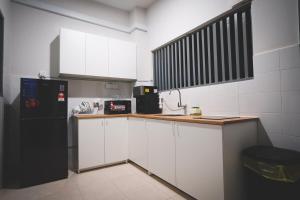 a kitchen with white cabinets and a black refrigerator at HM Residence 11pax Setia City Convention in Shah Alam