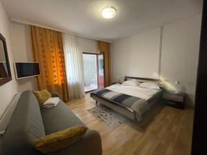 a bedroom with a bed and a couch at Gama House & Garden with restaurant in Vişeu de Sus