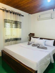 a bedroom with a large white bed with a window at Jaya Residence - Near Airport in Negombo