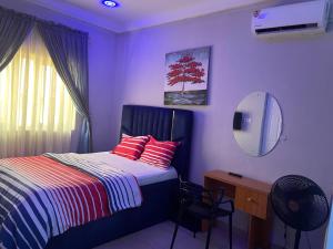 a bedroom with a bed and a desk with a mirror at Mega Pavilion Apartment Gwarinpa in Gwarinpa