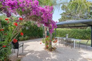 un arbre couvert de fleurs violettes à côté d'une table et de bancs dans l'établissement GuestHost - Casa Rosamarina Ostuni, à Rosa Marina 17 autres photos