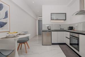 a white kitchen with a table and a counter top at Kassiopi Piazza Suites in Kassiopi