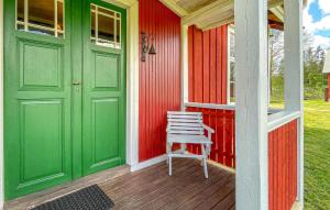 ein rotes Haus mit einer grünen Tür und einem Stuhl auf einer Veranda in der Unterkunft 3 Bedroom Pet Friendly Home In Grimsås in Grimsås