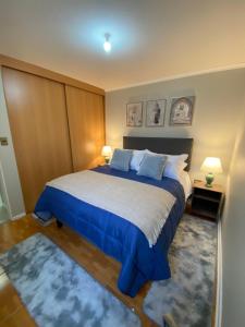 um quarto com uma cama grande com lençóis e almofadas azuis em Departamento 3 domitorios, a dos cuadras de Espacio Urbano, Terminal de Buses y Sodimac em Linares