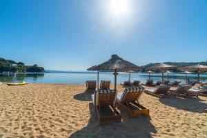 a beach with chairs and umbrellas on the sand at Amouage Boutique Home in Skiathos