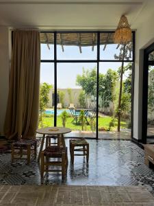 a living room with a table and chairs and a large window at Villa familiale, piscine privée sans vis-à-vis in Marrakech
