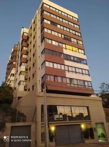a tall building with a parking garage in front of it at APT Por do Sol in Bento Gonçalves