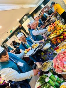 a group of people sitting at a buffet line with food at فندق مراج طيبه Mirage Taiba Hotel in Medina