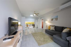 a living room with a couch and a flat screen tv at Casa Limão - Senhora da Rocha, Algarve in Porches