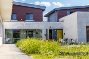 a building with glass doors and chairs in a yard at Auberge de Jeunesse HI Pontarlier in Pontarlier