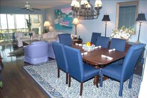 a living room with a wooden table and blue chairs at Crescent Royale 415 in Siesta Key