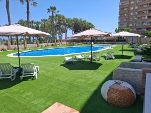 ein Swimmingpool mit Liegestühlen und Sonnenschirmen in der Unterkunft Ayf 3 habitaciones en 1ªlinea de playa costa in Oropesa del Mar