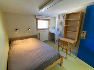 a small bedroom with a bed and a chair at Auberge de Jeunesse HI Pontarlier in Pontarlier