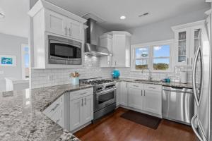 een keuken met witte kasten en roestvrijstalen apparaten bij Ocean View Pool Waterslide Elevator & Firepit in Oak Island