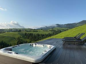 a hot tub on top of a wooden deck with a chair at Vershe in Verkhovyna